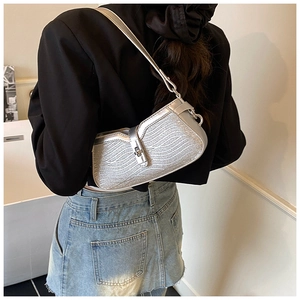 Silver baguette bag with wave relief texture and metal clasp shown on a model
