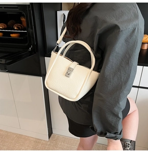 Détail du sac seau blanc en cuir grainé avec fermoir argenté dans une boulangerie cosy