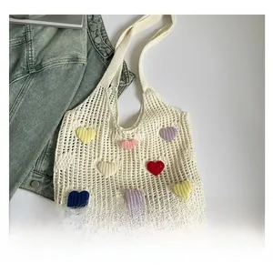 Detailed close-up of white crochet tote bag with colorful heart-shaped patches and knit texture