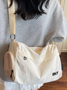 Sac de voyage minimaliste en nylon beige avec imprimé BNT et poche latérale en filet pratique
