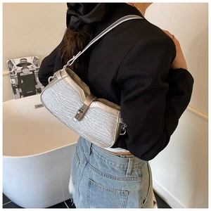 Detailed view of silver glittery baguette bag with wavy texture and metallic clasp buckle