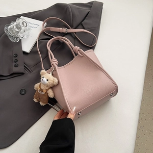 Vue détaillée du sac à main rose en cuir grainé avec breloque ours et rivets de protection