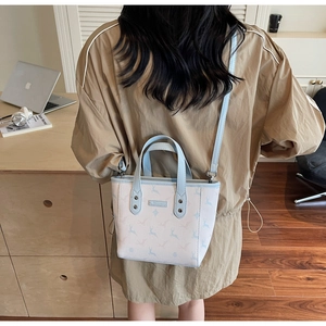 Detail view of stylish light blue deer print handbag shown on model in a cozy indoor setting