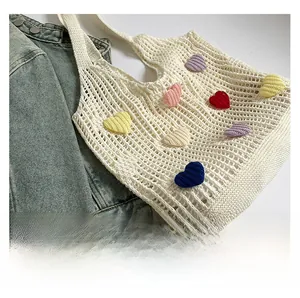 Close-up of crochet mesh tote bag with colorful knitted heart patches and woven texture