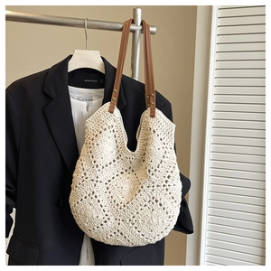 Detail of hand-woven hollow crochet beach bag with brown faux leather straps and metal rivets