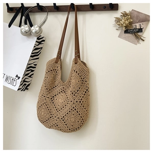 Detail of beige crochet tote bag with hollow diamond pattern and brown faux leather handle