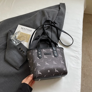 Close-up of dark grey patterned handbag with metallic feet and adjustable shoulder strap
