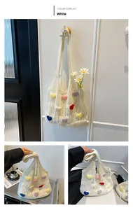 Detailed close-up of a white hand-knitted tote bag featuring colorful 3D heart-shaped patches
