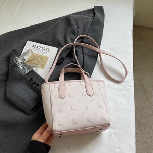 Detail of light pink leather handbag with deer pattern, adjustable strap and metal studs