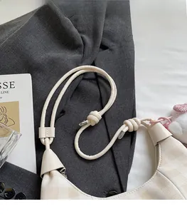 Detail of cream checkered dumpling bag showing knot strap and metal decorative elements