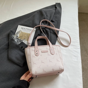 Detail of a pink and cream tote bag with deer prints and metal rivets on bottom