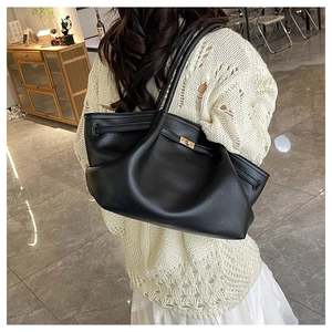 Detail of black leather tote bag featuring gold metal buckle and strap on back display