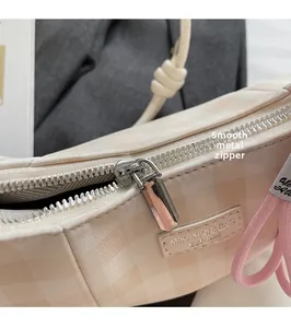 Close-up of smooth metal zipper and checkered pattern on the beige shoulder bag