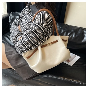 Detail of cream tote bag featuring textured lychee leather and golden square twist lock