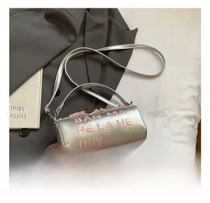 Détail du sac cylindrique argenté avec lettrage rose et bordure à volants délicate