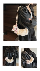 Detail view of cream checkered crescent bag with Hello Kitty plush charm and strap
