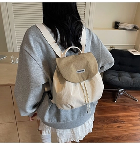 Detail view of the drawstring closure and logo patch on the stylish two-tone backpack
