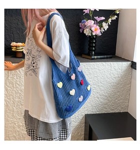 Lifestyle view of large knitted hollow tote bag with colorful heart patches on female model