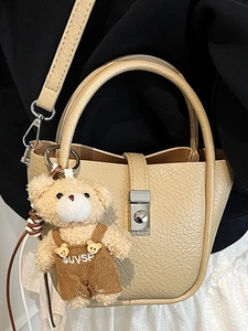 Sac seau chic en cuir beige avec pendentif ours et fermoir métallique pour femme