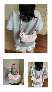 Detail of pink plaid crescent bag with adjustable strap and soft plush pendant