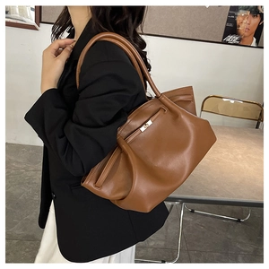 Brown leather underarm bag with metal buckle and strap details shown on a female model