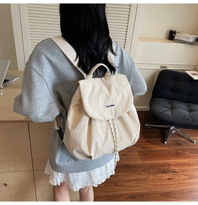 Detail view of cream drawstring backpack with adjustable straps and front flap closure
