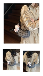 Detail view of grey checkered shoulder bag with a plush white cat charm on a staircase