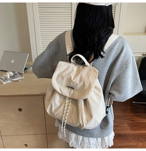 Detail of cream drawstring backpack showing lightweight textured fabric and logo patch