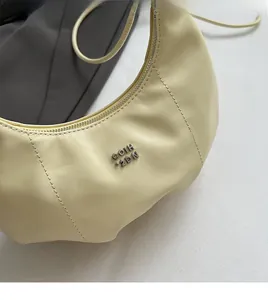 Nahaufnahme der beigefarbenen Hobo-Tasche mit Ledertextur und silbernem Metalllogo