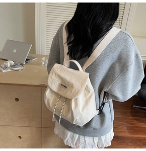 Lifestyle shot of cream white nylon backpack with flap closure and drawstring detail