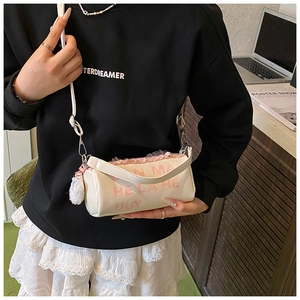 Détail d'un sac bandoulière blanc cylindrique avec dentelle rose et pompon doux