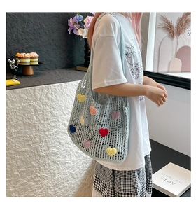 Close-up of light blue crochet tote bag with colorful 3D heart-shaped knit patches