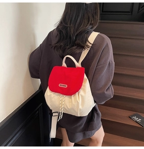 Close-up of color-block backpack featuring a red flap, cream body, and drawstring closure