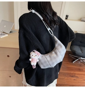 Detail of silver checkered dumpling bag with a cute plush kitty charm on side
