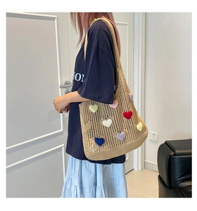 Detailed knit texture of large woven tote bag with colorful 3D heart-shaped crochet patches