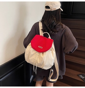 Detail of cream and red canvas backpack featuring brand label and drawstrings