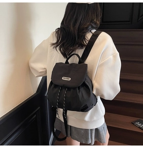Close-up of minimalist black drawstring backpack on model showing stylish urban look