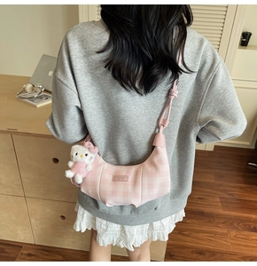 Back view of model wearing pink plaid crescent bag with cute plush doll charm