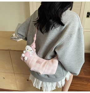 Detail shot of a pink checkered dumpling bag with a cute plush character charm accessory