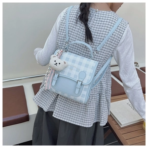 Detail of light blue checkered backpack with cute bear pendant and leather straps