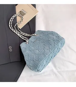 Detail of light blue denim handbag featuring pleated texture and silver chain strap