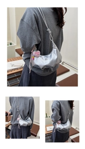 Detail der silbernen Metallic-Hobo-Tasche mit rosa Herzanhänger und geknotetem Schultergurt