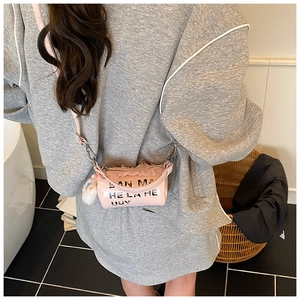 Détail d'un sac bandoulière cylindrique rose avec bordure en dentelle et pompon doux