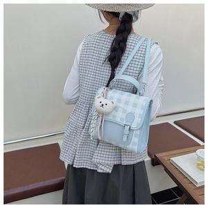 Detail of light blue checkered backpack with plush bear charm and sturdy top handle strap