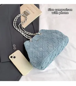 Blue pleated textured crossbody bag with silver chain strap shown next to a smartphone