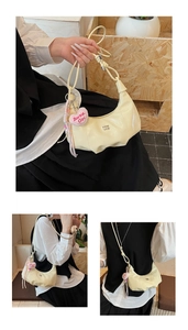 Detail der beigen sichelförmigen Schultertasche mit Knotengriff und Barbie-Anhänger