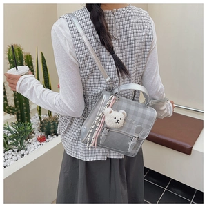 Detail of silver plaid backpack with metallic leather texture and cute plush bear charm