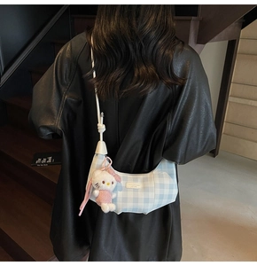 Detail of blue and white plaid dumpling bag with adjustable strap worn on the back