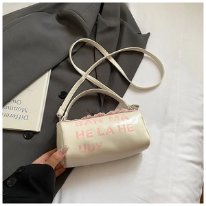 Détail d'un sac baril blanc crème avec bordure à volants roses et imprimé logo chic