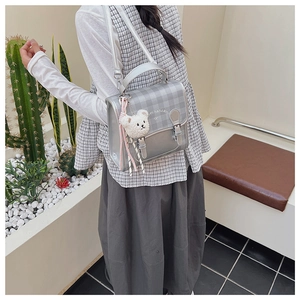 Detail of silver plaid satchel with cute plush bear charm and striped ribbon strap